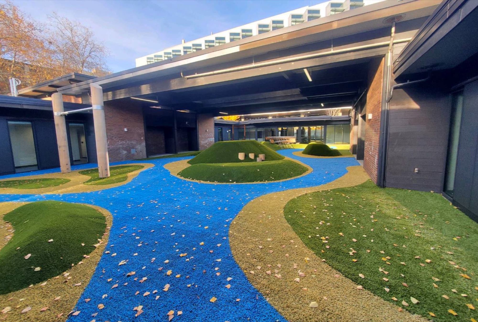 The EEU's covered outdoor play area: turf mounds and a winding blue path under a roof overhang.